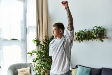 Genç yakışıklı adam bitkilerle dolu parlak bir yaşam alanına rahatça uzanır..