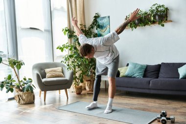 Protez bacaklı genç bir adam yaşam alanında yoga yapıyor, gücünü gösteriyor..