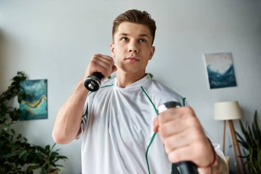 Kararlı genç adam dambıllar kullanarak egzersiz yapar, yolculuğunda güç ve direnç gösterir..