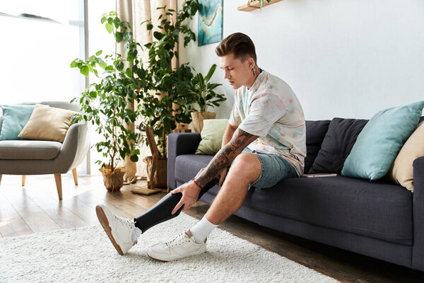 Человек сидит на диване, регулируя свою протезную ногу, обнимая расслабленную атмосферу.