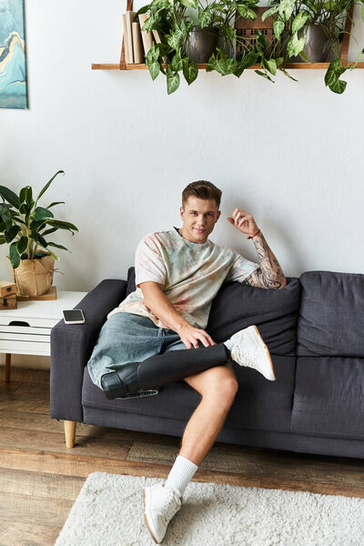 Красивый молодой человек наслаждается моментом отдыха на уютном диване в окружении растений и солнечного света.