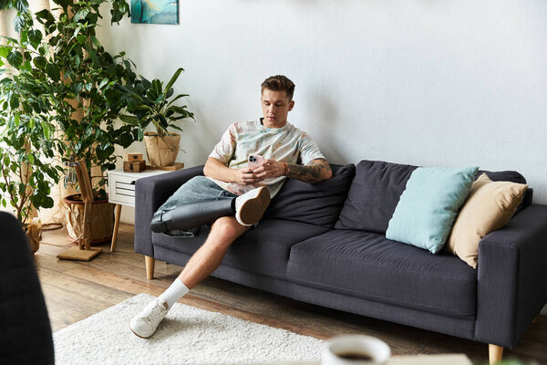Stylish young man with a prosthetic leg uses his smartphone in a chic living room.