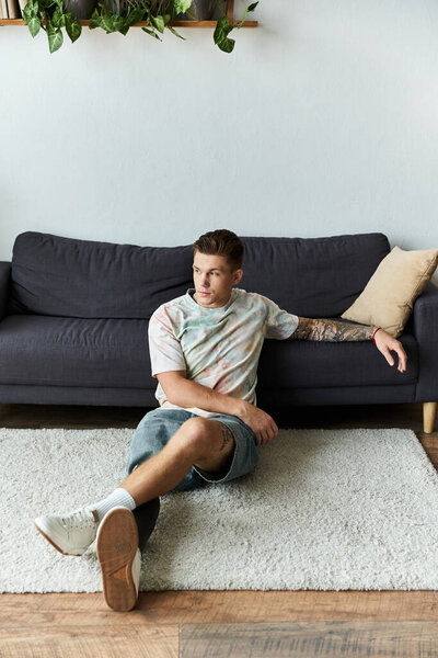 Красивый молодой человек удобно сидит на уютном ковре, демонстрируя свою протезную ногу в современном пространстве..
