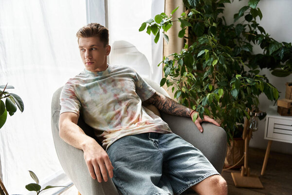 Красивый молодой человек сидит удобно в уютном кресле, демонстрируя свой уникальный стиль и уверенность.
