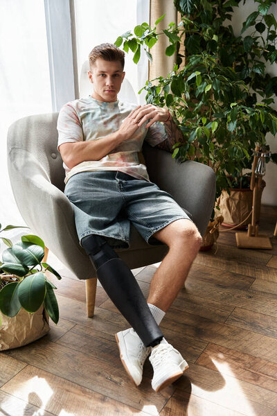 Красивый молодой человек, удобно сидящий в кресле, демонстрирует свою протезную ногу и стиль.