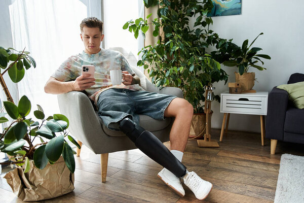 Расслабляясь в уютном кресле, молодой человек с протезной ногой проверяет телефон, потягивая кофе..
