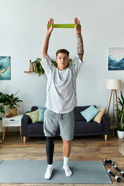 In a bright living room, a young man with a prosthetic leg lifts a resistance band.