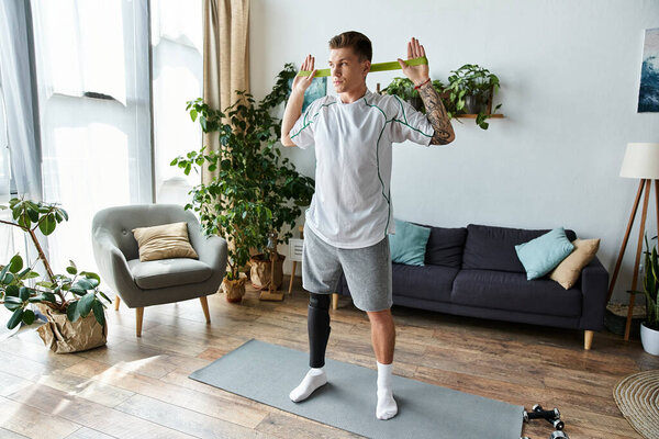 Handsome young man engages in a workout routine at home with a prosthetic leg and resistance band.