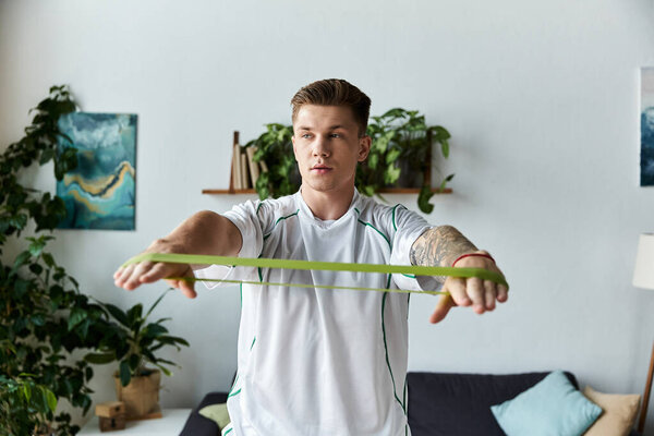 Handsome young man engages in fitness routine using resistance bands in a bright indoor setting.