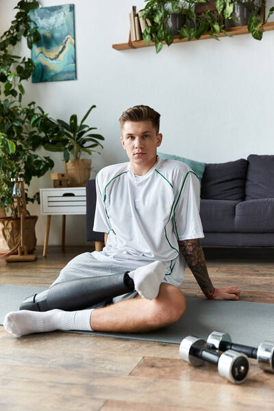 Молодой человек с протезной ногой сидит на коврике, демонстрируя решимость и физическую форму дома.