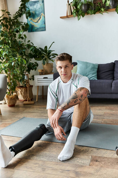 Красивый молодой человек с протезной ногой расслабляется на коврике для йоги в яркой, стильной комнате.