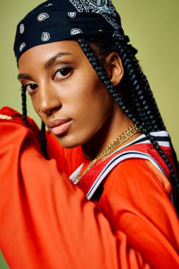 Cesur kırmızı elbiseli genç bir kadın kameraya güvenli bir şekilde poz veriyor..