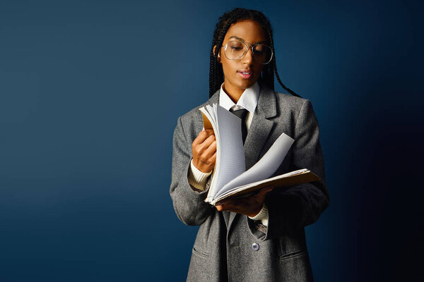 Focused young woman flipping through her notes while dressed in a chic oversized outfit