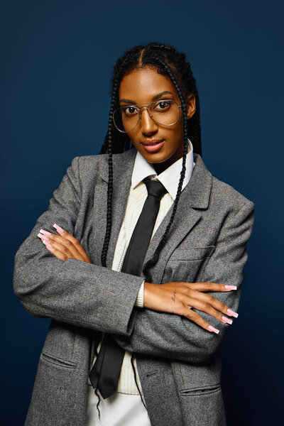 A confident young woman poses with crossed arms in stylish professional attire.