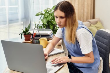 A teenage girl focused on her laptop, surrounded by plants and notebooks in her cozy room. clipart