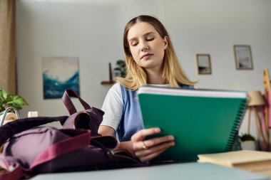 Güzel genç kız odasında oturmuş, rahat bir atmosferde çalışma materyalleriyle uğraşıyor..