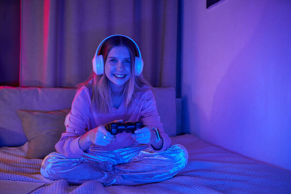 A young girl enjoys playing video games in her cozy, colorful room during the evening.