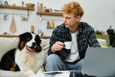 Kızıl saçlı genç bir adam evdeki Avustralyalı çobanıyla samimi bir anı paylaşıyor..