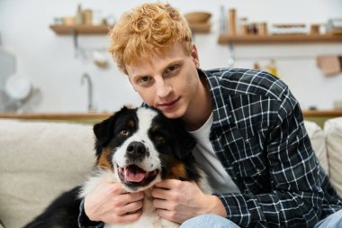 Genç bir kızıl, Avustralya çoban köpeğini modern bir evde kucaklıyor, neşeyi paylaşıyor..