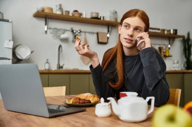 Evde dinlenen genç bir adam, mutfakta kahvaltının tadını çıkarırken telefonda sohbet ediyor..