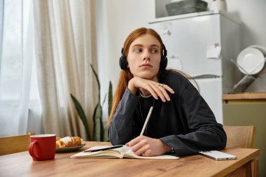İyi görünümlü genç bir adam modern dairesinde oturur, müzik dinlerken düşüncelere dalmıştır..
