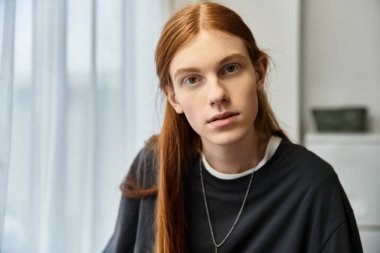 Uzun saçlı yakışıklı genç bir adam şık dairesinde rahat bir havanın tadını çıkarıyor..