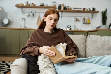 Genç adam şık evinde rahat giyinip kitap okurken sakin bir anın tadını çıkarıyor..