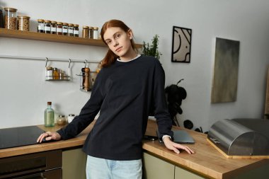 Yakışıklı, kızıl saçlı genç bir adam şık dairesinde dikiliyor ve eğleniyor..