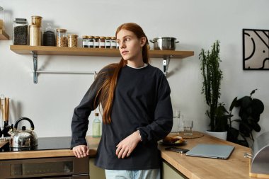 Uzun kızıl saçlı, sweatshirt giyen genç adam rahat apartman hayatının tadını çıkarıyor..