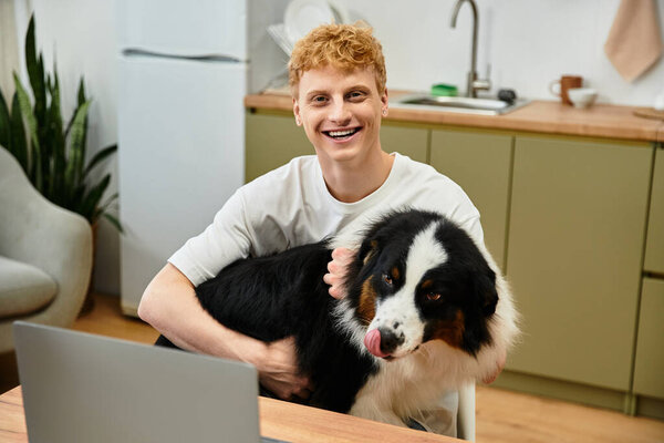 Молодой человек смеется, обнимая своего австралийского пастуха в современной обстановке квартиры.