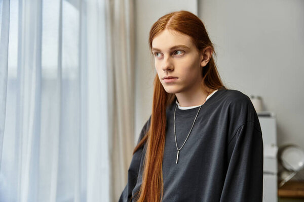 A young, stylish guy with long hair relaxes in his cozy apartment, embracing a peaceful moment.