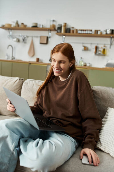 Молодой парень с длинными рыжими волосами расслабляется в своей стильной квартире, используя ноутбук.