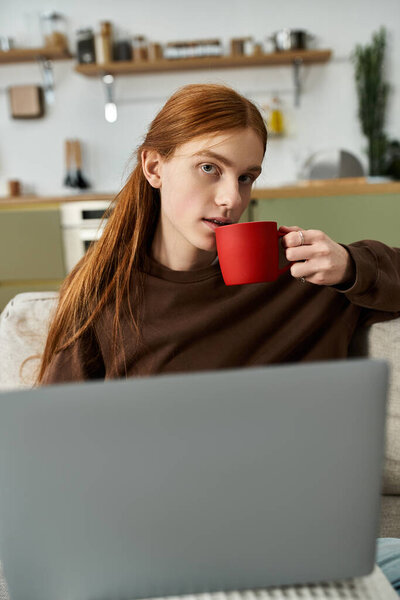 Очаровательный молодой человек расслабляется в своей стильной квартире, наслаждаясь теплой чашкой кофе.