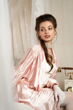 Ruhsal çekiciliği olan güzel genç bir kadın düşünceli bir şekilde eski moda bir odaya bakıyor..