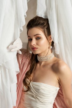 Genç ve güzel bir kadın zarif bir şekilde dalgalanan kumaşın ortasında duruyor, rüya gibi, mistik bir titreşim yayıyor..