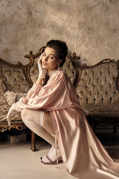 В хорошо освещенной комнате молодая женщина в винтажном стиле излучает мистическую элегантность.