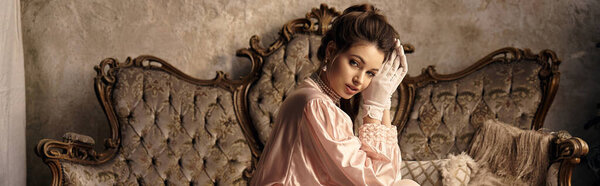 A vintage clad young woman poses gracefully in a mystical, elegant setting.