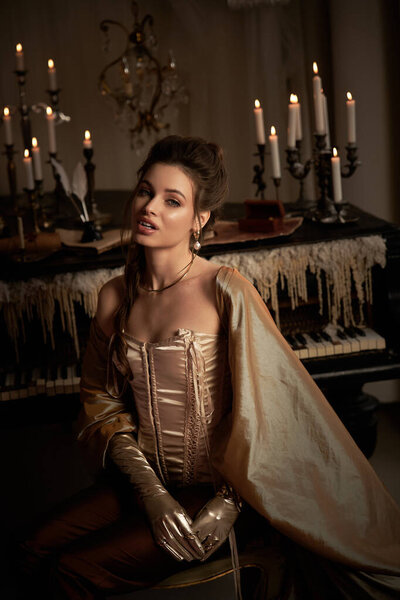 A young woman embodies a vampire allure while seated in a dim, enchanting room adorned with candles.