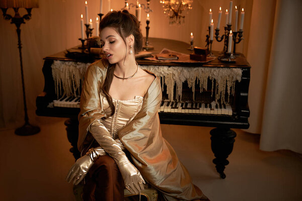 A young woman in elegant attire sits gracefully by a grand piano, surrounded by candles.