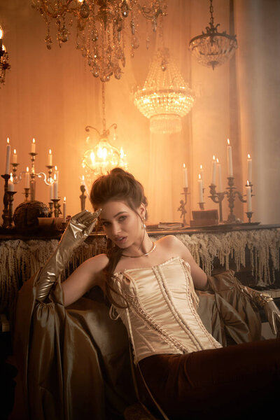 A beautiful young woman reclines gracefully, embodying a mystical vampire in an opulent setting.