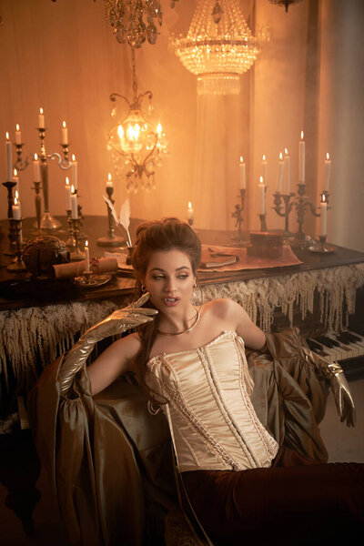 A young woman with enchanting features lounges in a candlelit room, radiating mystery.