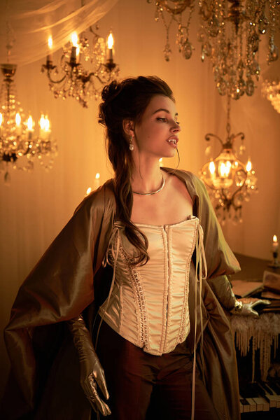 Молодая женщина в костюме вампира грациозно стоит под мерцающими люстрами.