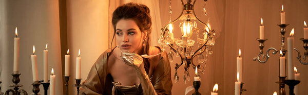 A beautiful young woman in candlelight exudes a captivating vampire mystique.