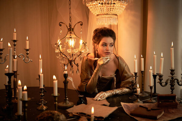 Красивый вампир элегантно сидит за столом при свечах, потерявшись в мыслях.