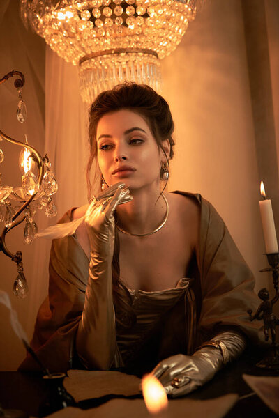 В светлой комнате молодая женщина в элегантной одежде пишет мистические секреты при свете свечей..