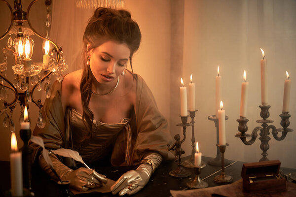 A young woman in a vampire costume writes thoughtfully by candlelight, shrouded in mystery.