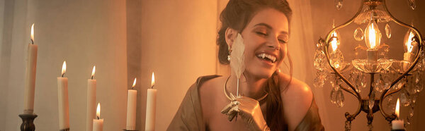 A young woman enjoys a captivating moment amid flickering candles and a sparkling chandelier.