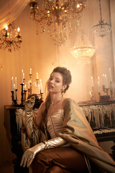 A young woman dressed as a mystical vampire lounges elegantly, exuding allure in a grand room.