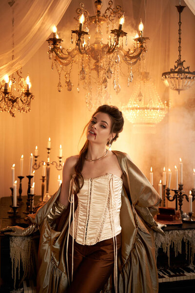 A confident young woman in elegant attire stands in a dimly lit ballroom surrounded by candles.