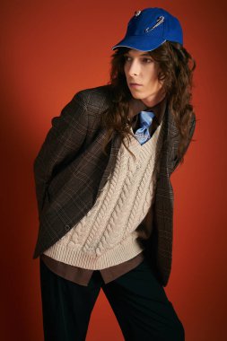 Genç bir adam, katmanları ve aksesuarları olan, kendine güveni ve yeteneği olan şık bir kıyafet sunar..